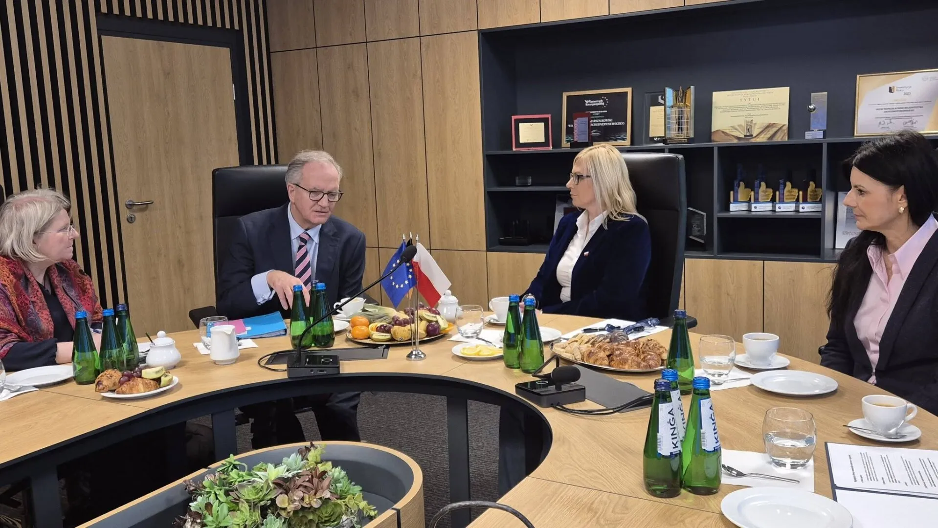 Konsul generalny i wicemarszałkini rozmawiają przy owalnym stole prezydialnym, w tle wystrój pomieszczenia.