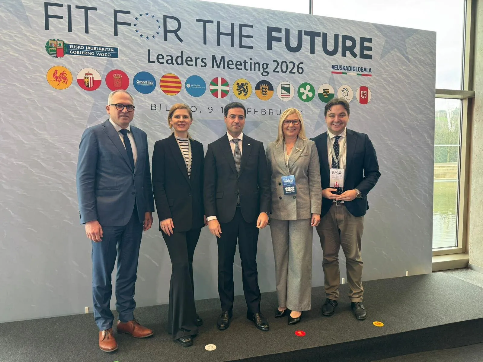 Goście wydarzenia stoją na ściance promującej przedsięwzięcie.