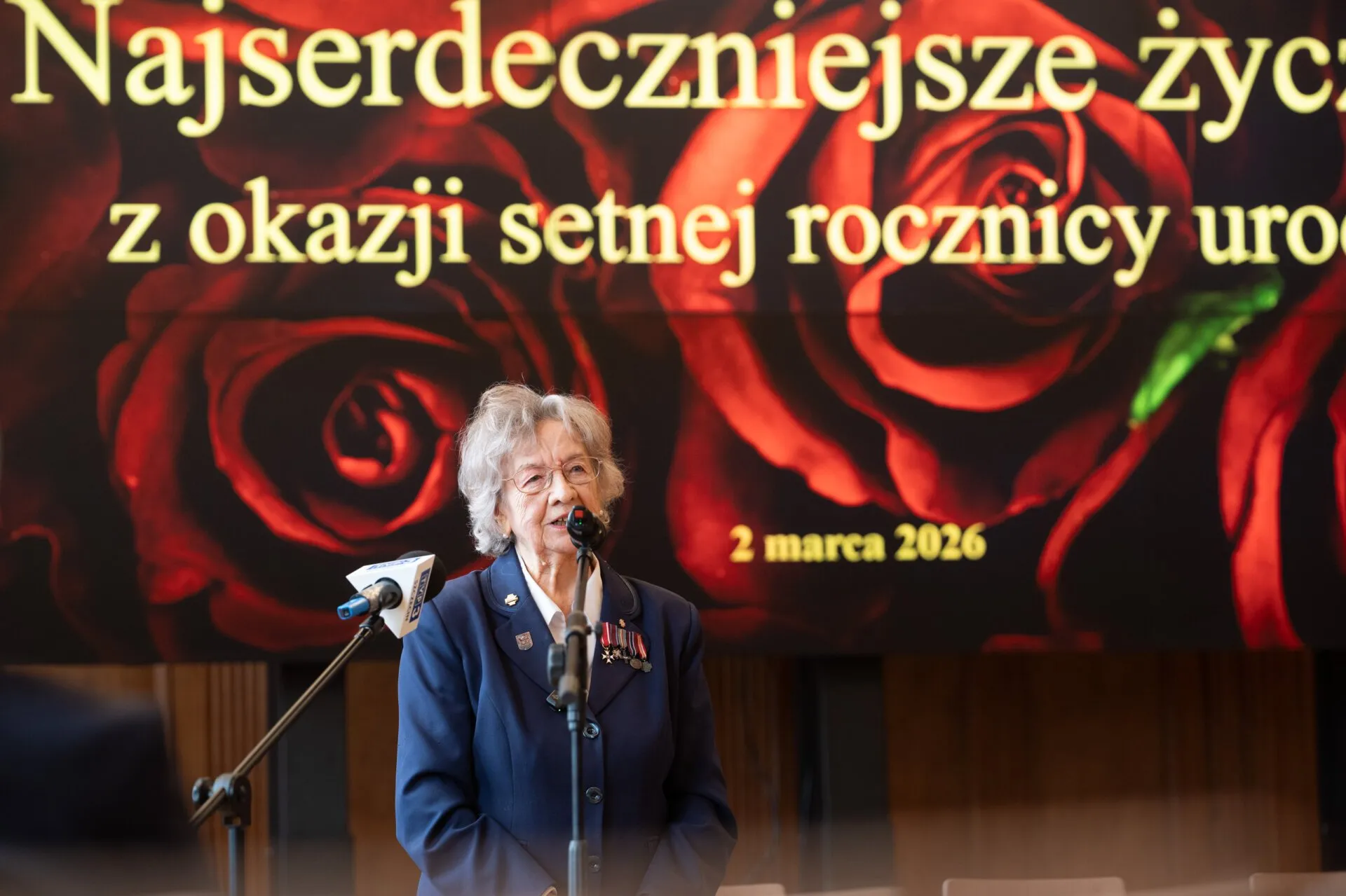 Jubilatka przemawia, w tle slajd z okazji urodzin.