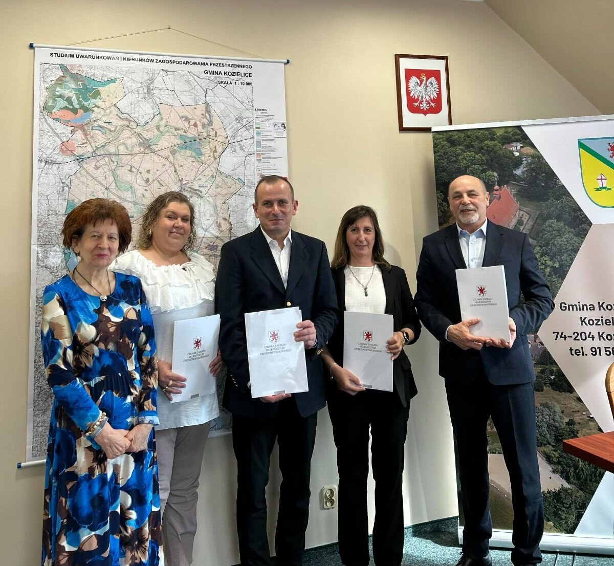 Strony prezentuja podpisane umowy, w tle mapa województwa - fot. Urząd Gminy Kozielice.