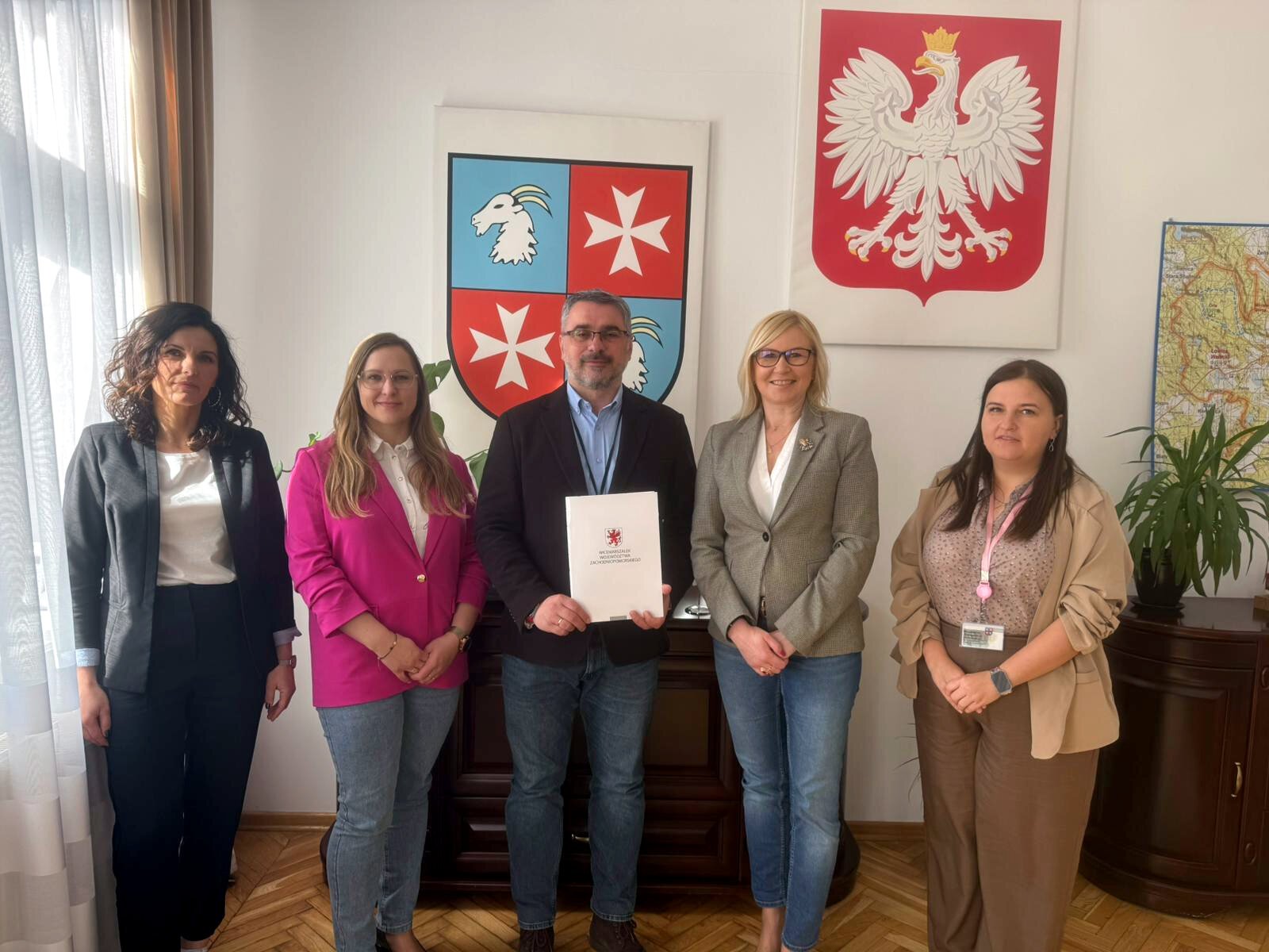 Strony umowy prezentują podpisany dokument, w tle godło Polski i herb Mirosławca.