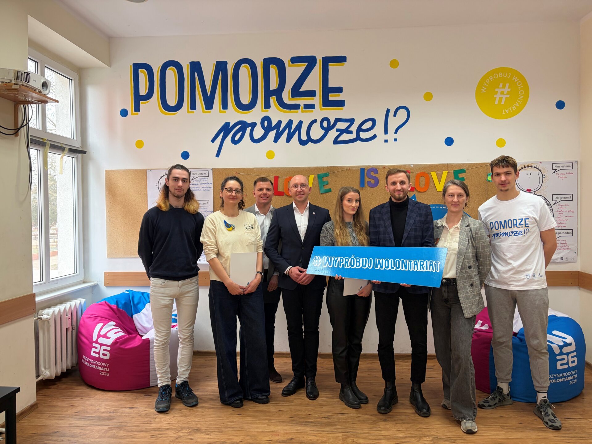 Zdjęcie grupowe uczestników spotkania na tle napisu POMORZE pomoże?