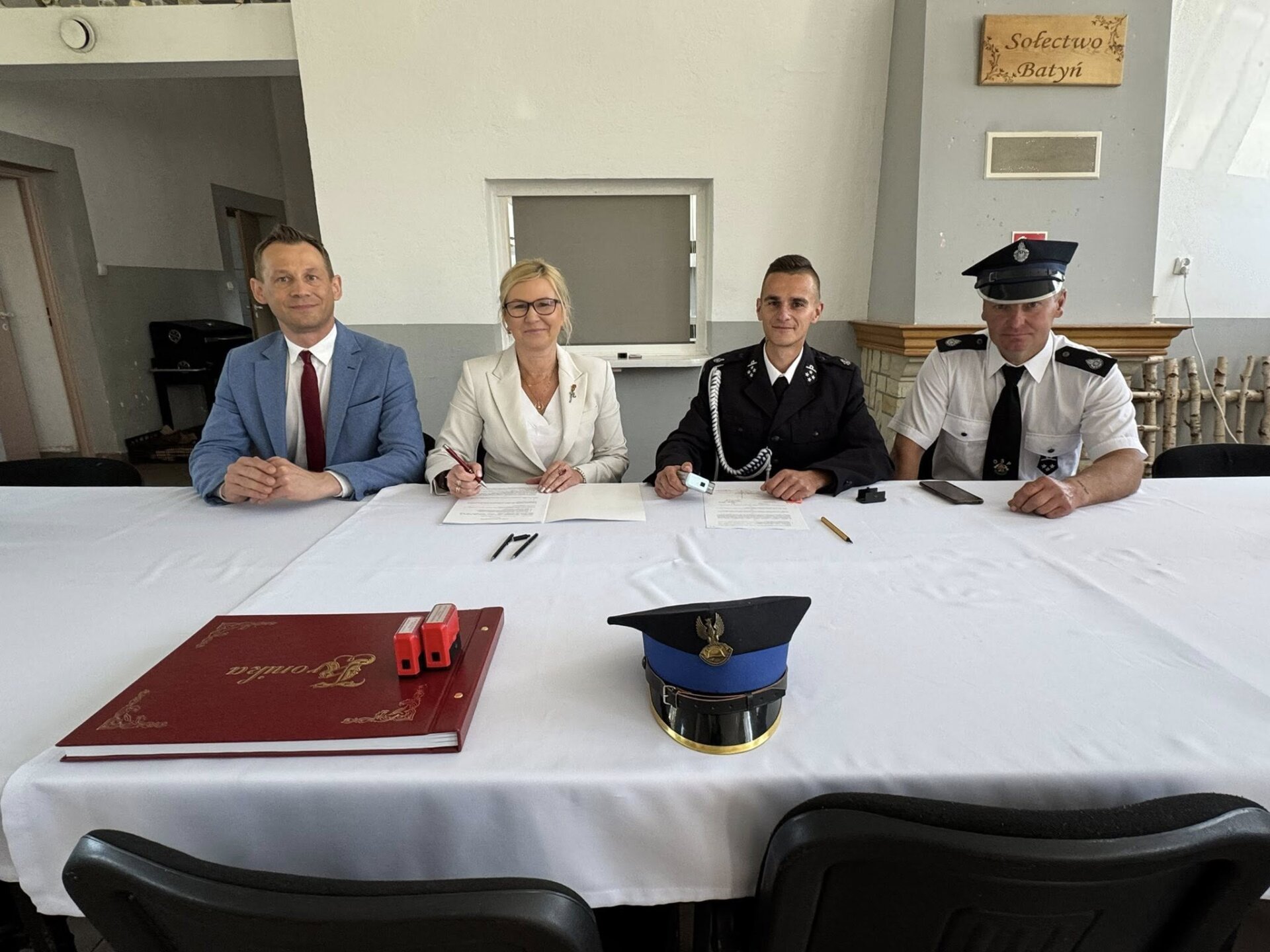 podpisanie umowy przez wicemarszałek z OSP, na pierwszym planie album i czapka