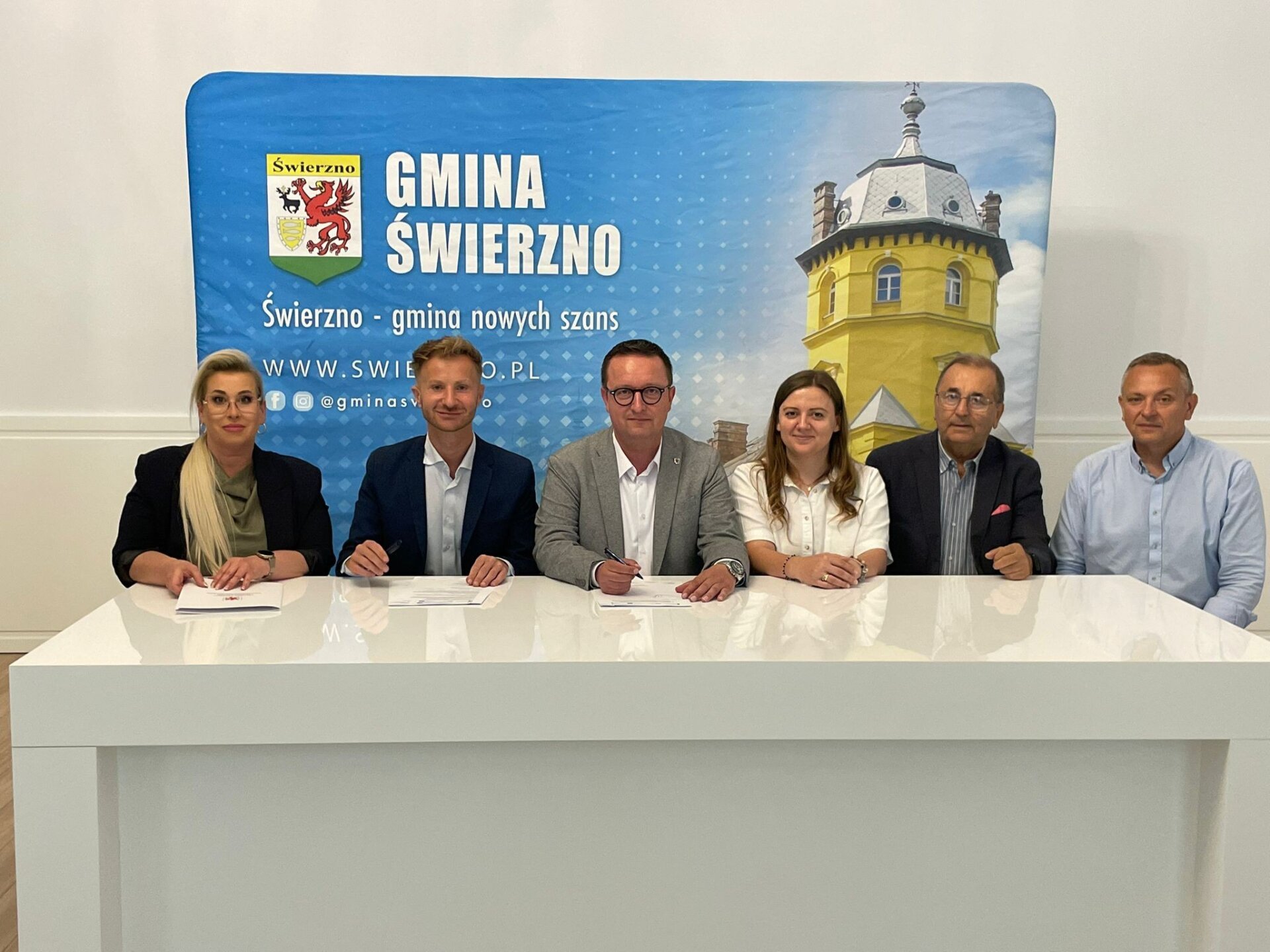 podpisanie umowy przez samorządowców, w tle ścianka promocyjna z napisem Gmina Świerzno