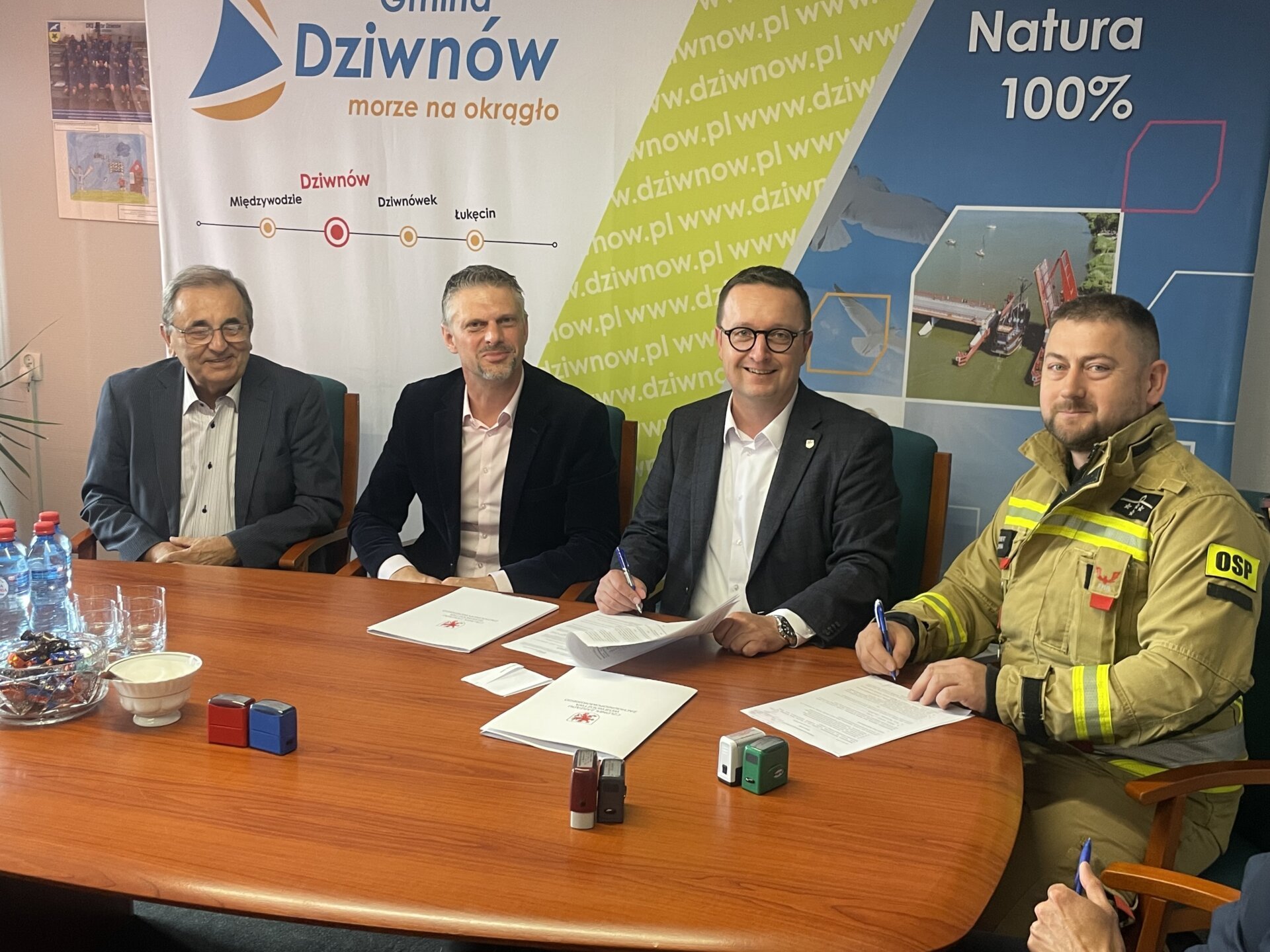 podpisanie umowy w Urzędzie Miejskim w Dziwnowie, za stołem siedzą urzędnicy i strażak OSP