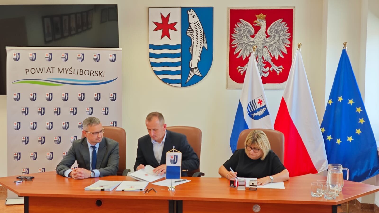 Strony umowy podpisują umowy za stołem prezydialnym.