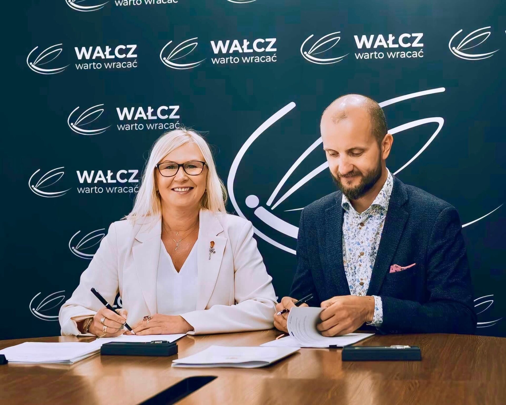 Anna Bańkowska oraz Maciej Żebrowski podpisują umowę, w tle ścianka promocyjna z nazwą miejscowości Wałcz