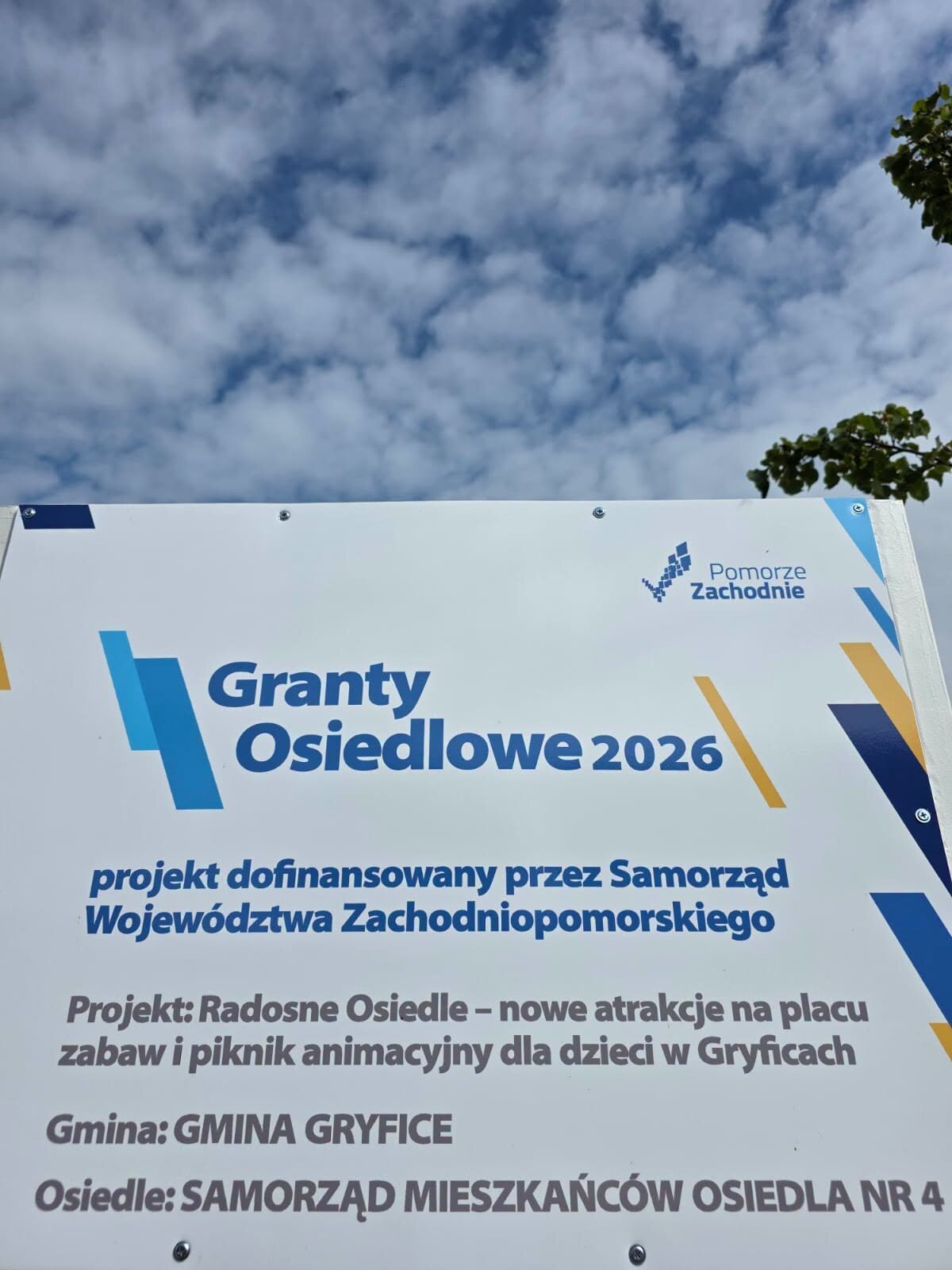 tablica informacyjna z napisem granty osiedlowe 2026 na białym tle, niebieskie napisy projekt dofinansowany przez Samorząd Województwa Zachodniopomorskiego